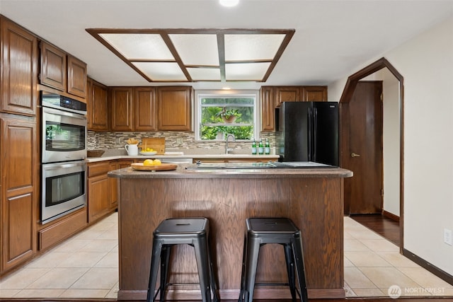8037 Incline Dr SE, Olympia, WA 98513 - kitchen with stainless steel double oven, freestanding refrigerator, a center island, decorative backsplash, and a kitchen bar