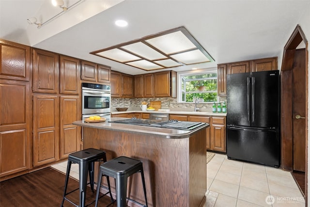 8037 Incline Dr SE, Olympia, WA 98513 - kitchen featuring freestanding refrigerator, double oven, a breakfast bar area, and brown cabinetry