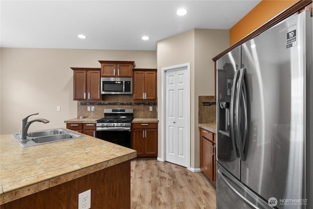18328 73rd Avenue Ct E, Puyallup, WA 98375 - kitchen with stainless steel appliances, light wood-style flooring, tasteful backsplash, brown cabinets, and recessed lighting