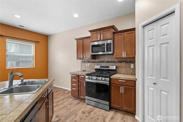 18328 73rd Avenue Ct E, Puyallup, WA 98375 - kitchen with appliances with stainless steel finishes, light wood-style flooring, backsplash, brown cabinets, and recessed lighting
