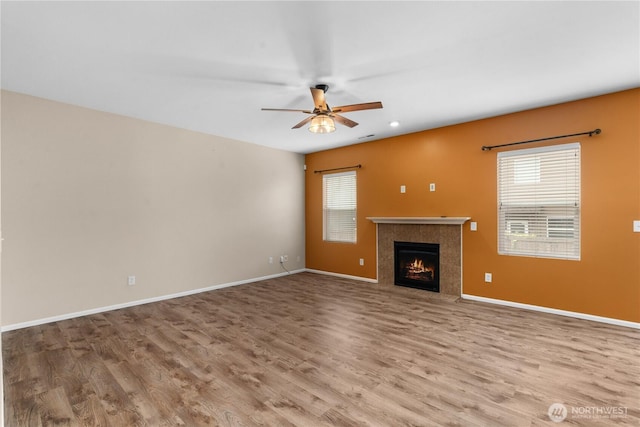 18328 73rd Avenue Ct E, Puyallup, WA 98375 - unfurnished living room featuring wood finished floors, a ceiling fan, and a lit fireplace