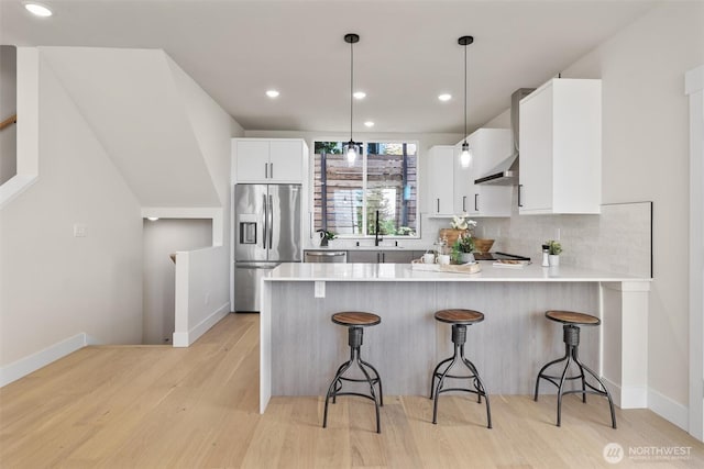 1313 14th Ave S Unit B, Seattle, WA 98144 - kitchen with appliances with stainless steel finishes, a peninsula, light wood-style floors, a breakfast bar, and light countertops