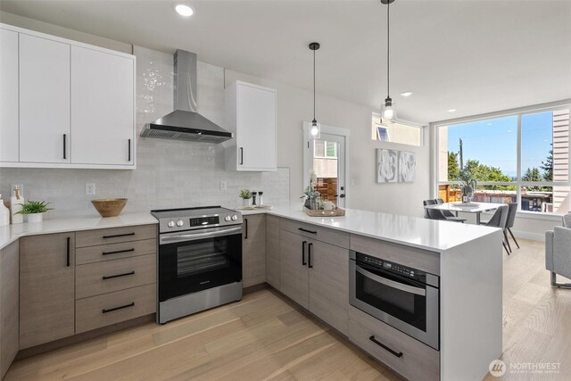 1313 14th Ave S Unit B, Seattle, WA 98144 - kitchen featuring wall chimney range hood, electric stove, a peninsula, light countertops, and light wood-style floors