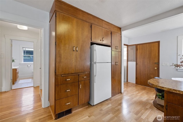 4335 Fawcett Ave, Tacoma, WA 98418 - kitchen featuring freestanding refrigerator, light wood-style floors, and brown cabinetry