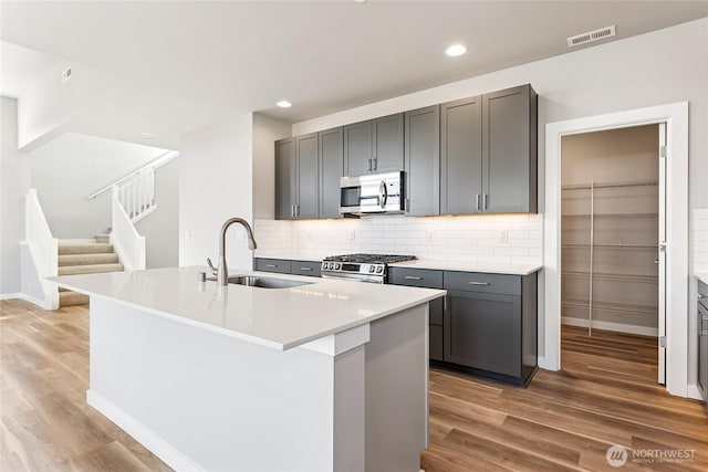 13936 178th St E Unit 85, Puyallup, WA 98374 - kitchen featuring stainless steel appliances, light wood-style flooring, backsplash, a center island with sink, and recessed lighting