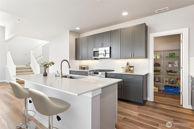 13936 178th St E Unit 85, Puyallup, WA 98374 - kitchen featuring stainless steel appliances, a breakfast bar, light wood finished floors, gray cabinets, and recessed lighting