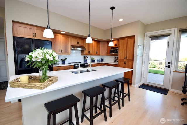 771 Brigadoon Blvd, Sequim, WA 98382 - kitchen featuring stainless steel microwave, under cabinet range hood, light wood-style flooring, backsplash, and recessed lighting