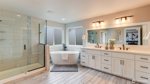 23000 SE Sycamore St, Black Diamond, WA 98010 - full bathroom featuring double vanity, a stall shower, a freestanding tub, wood finished floors, and recessed lighting