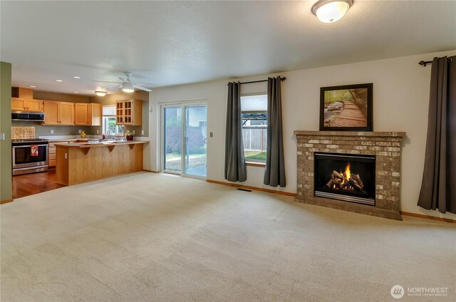 4101 Alabaster St SE, Lacey, WA 98503 - kitchen with appliances with stainless steel finishes, open floor plan, light brown cabinetry, glass insert cabinets, and a fireplace