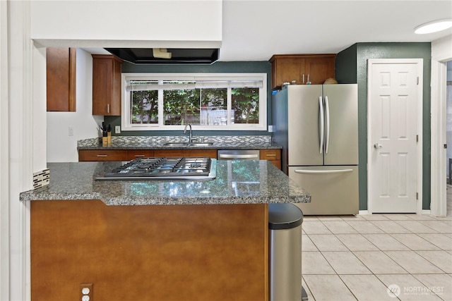 19031 SE 266th St, Covington, WA 98042 - kitchen with stainless steel appliances, light tile patterned floors, brown cabinets, dark stone counters, and a peninsula