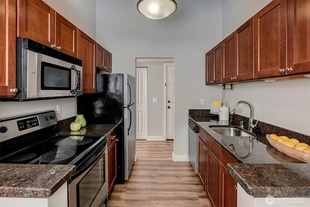 15819 NE Leary Way Unit D302, Redmond, WA 98052 - kitchen featuring appliances with stainless steel finishes, light wood-type flooring, dark stone counters, and a towering ceiling