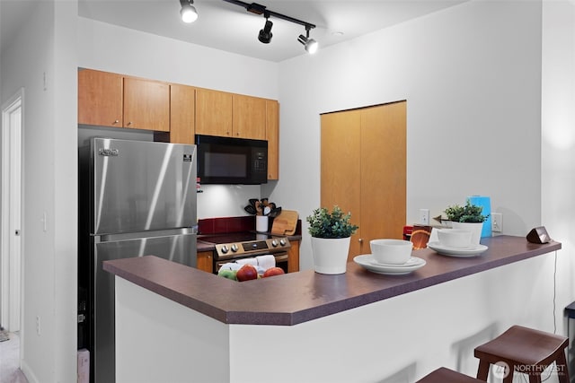 668 S Lane St Unit 603, Seattle, WA 98104 - kitchen featuring appliances with stainless steel finishes, dark countertops, a peninsula, and a kitchen bar