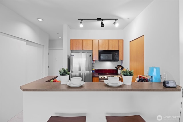 668 S Lane St Unit 603, Seattle, WA 98104 - kitchen with appliances with stainless steel finishes, a peninsula, a kitchen breakfast bar, dark countertops, and rail lighting