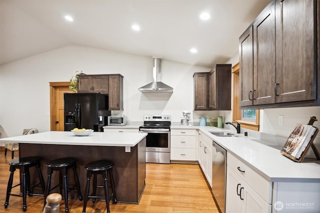 11211 Juniper Pl, Anderson Island, WA 98303 - kitchen with appliances with stainless steel finishes, wall chimney range hood, lofted ceiling, a kitchen breakfast bar, and dark brown cabinets