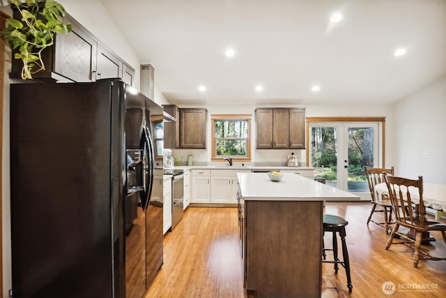 11211 Juniper Pl, Anderson Island, WA 98303 - kitchen with black fridge, stainless steel range with electric cooktop, a breakfast bar area, a kitchen island, and light countertops