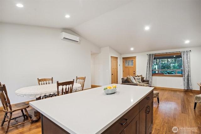 11211 Juniper Pl, Anderson Island, WA 98303 - kitchen with an AC wall unit, vaulted ceiling, light countertops, light wood finished floors, and a center island