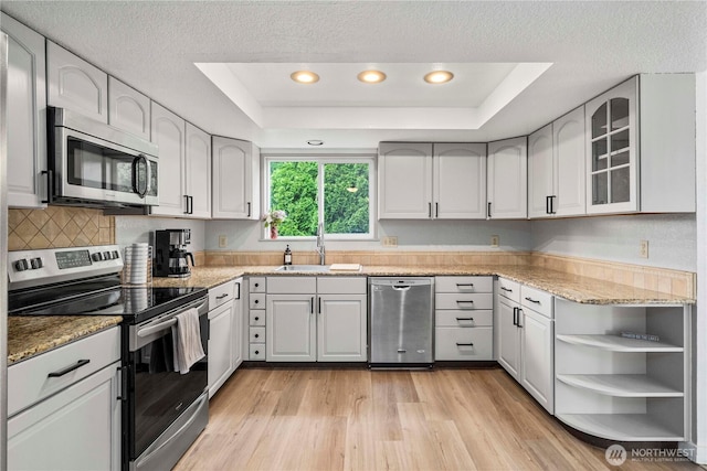 2505 211th Ave E, Lake Tapps, WA 98391 - kitchen featuring appliances with stainless steel finishes, a tray ceiling, light stone counters, light wood finished floors, and a textured ceiling