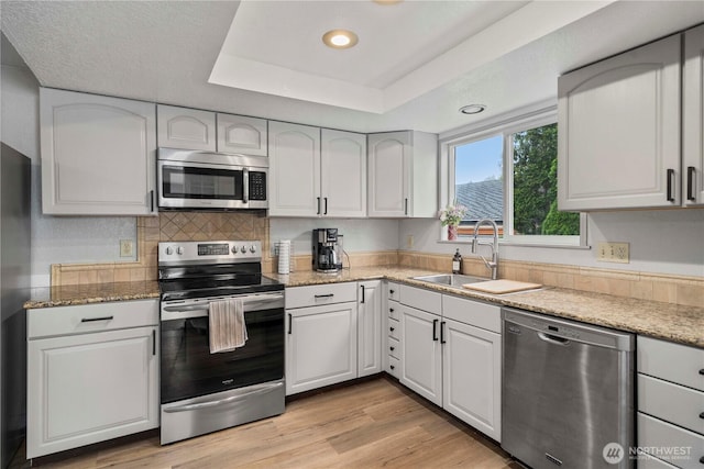 2505 211th Ave E, Lake Tapps, WA 98391 - kitchen with appliances with stainless steel finishes, a raised ceiling, light stone countertops, recessed lighting, and light wood-type flooring