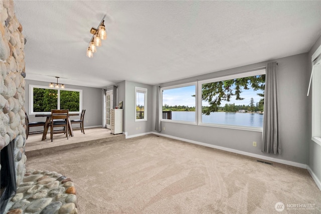 2505 211th Ave E, Lake Tapps, WA 98391 - unfurnished living room featuring carpet, a textured ceiling, a chandelier, and a water view