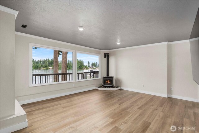 2505 211th Ave E, Lake Tapps, WA 98391 - unfurnished living room featuring a water view, light wood-style floors, a wood stove, a textured ceiling, and ornamental molding