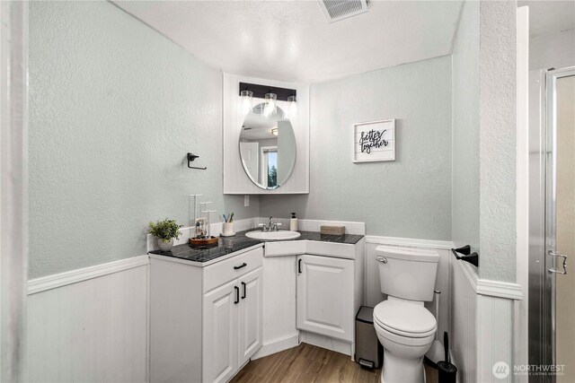 2505 211th Ave E, Lake Tapps, WA 98391 - bathroom with wood finished floors, vanity, a textured wall, a shower stall, and a wainscoted wall