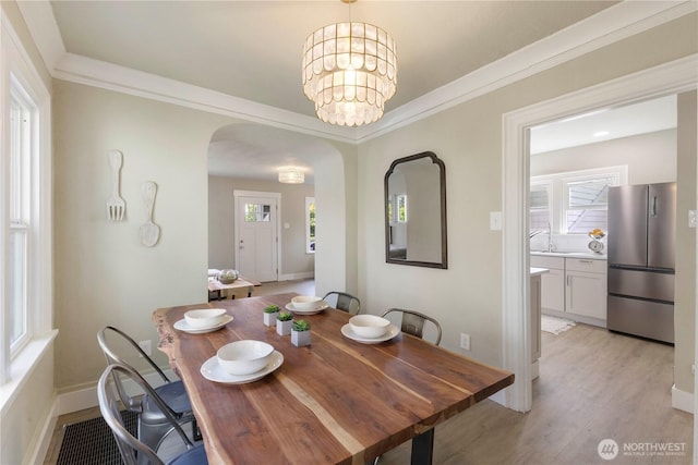 1206 S 14th St, Tacoma, WA 98405 - dining area featuring arched walkways, light wood-type flooring, a chandelier, and ornamental molding