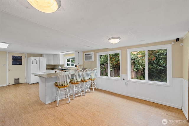 429 170th St S, Spanaway, WA 98387 - kitchen with freestanding refrigerator, light wood-style floors, a peninsula, a breakfast bar, and wainscoting