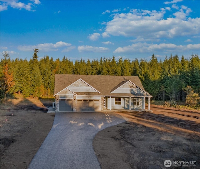 14317 Mima Rd SW, Olympia, WA 98512 - view of front of home with a wooded view, driveway, an attached garage, a porch, and stone siding