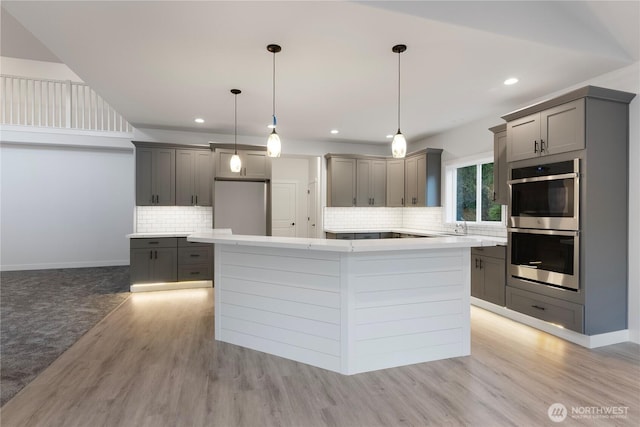 14317 Mima Rd SW, Olympia, WA 98512 - kitchen with gray cabinetry, double oven, a kitchen island, decorative backsplash, and recessed lighting