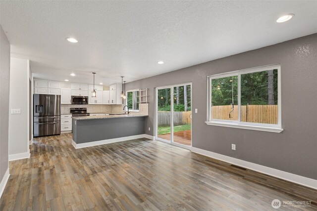 22415 Bluewater Dr SE, Yelm, WA 98597 - kitchen featuring stainless steel appliances, a peninsula, white cabinetry, dark wood-type flooring, and recessed lighting
