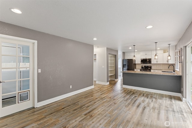 22415 Bluewater Dr SE, Yelm, WA 98597 - kitchen with appliances with stainless steel finishes, white cabinetry, wood finished floors, backsplash, and a peninsula