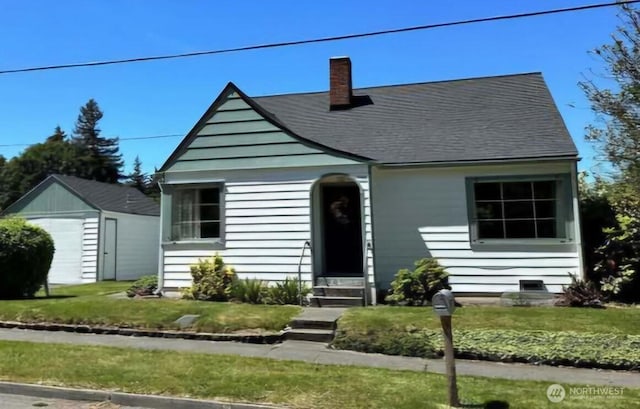 302 S Albert St, Port Angeles, WA 98362 - view of front of house with entry steps, a chimney, an outbuilding, a detached garage, and a front lawn