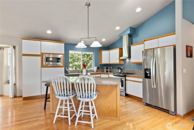 8615 176th St NW, Stanwood, WA 98282 - kitchen featuring stainless steel appliances, wall chimney range hood, a center island, white cabinets, and vaulted ceiling
