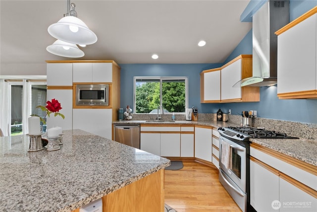 8615 176th St NW, Stanwood, WA 98282 - kitchen featuring stainless steel appliances, wall chimney range hood, white cabinetry, light wood-style floors, and pendant lighting