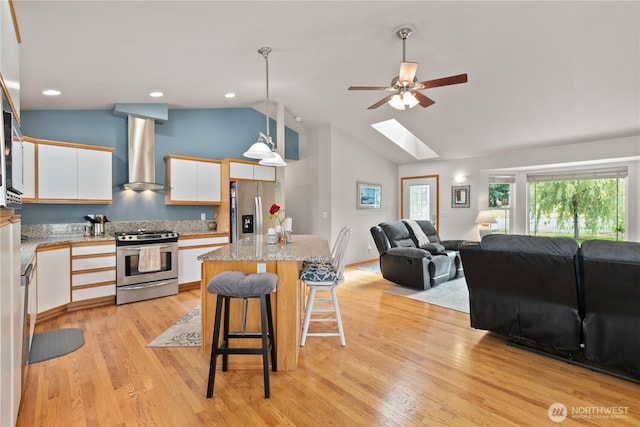 8615 176th St NW, Stanwood, WA 98282 - kitchen featuring stainless steel appliances, wall chimney exhaust hood, a skylight, white cabinetry, and open floor plan