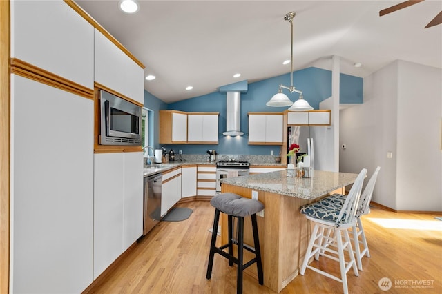 8615 176th St NW, Stanwood, WA 98282 - kitchen with appliances with stainless steel finishes, wall chimney exhaust hood, vaulted ceiling, white cabinetry, and a center island
