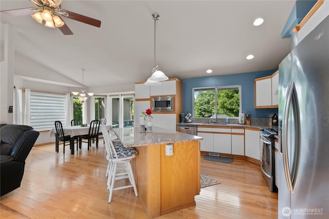 8615 176th St NW, Stanwood, WA 98282 - kitchen with appliances with stainless steel finishes, white cabinetry, light wood finished floors, a kitchen island, and decorative light fixtures