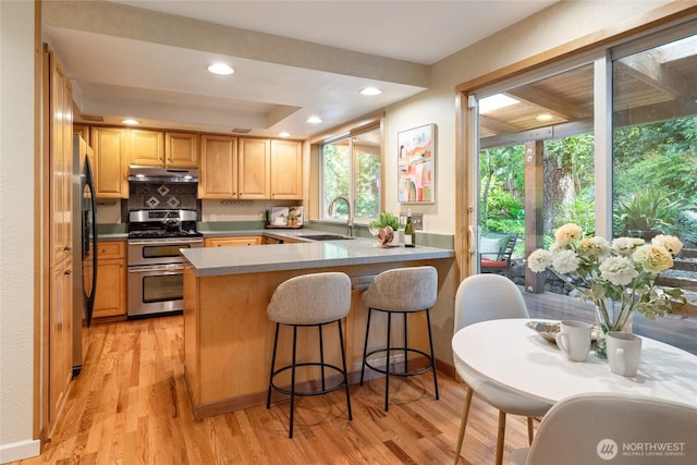 822 206th Ave NE, Sammamish, WA 98074 - kitchen with range with two ovens, under cabinet range hood, fridge with ice dispenser, light brown cabinetry, and a peninsula