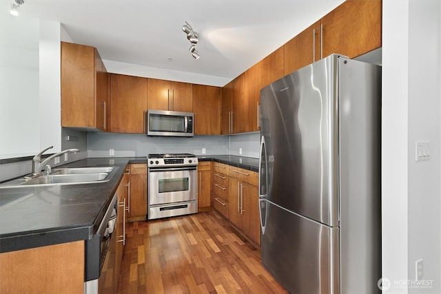 124 Bellevue Ave E Unit 504, Seattle, WA 98102 - kitchen featuring stainless steel appliances, dark countertops, light wood-style floors, and brown cabinetry