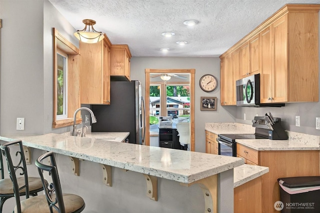 132 Tanglewood Dr, Longview, WA 98632 - kitchen featuring stainless steel appliances, a ceiling fan, a peninsula, light stone countertops, and a breakfast bar
