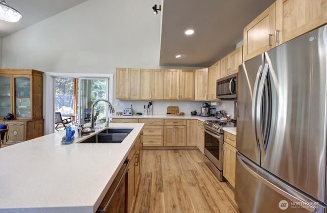 999 41st Ln, Seaview, WA 98644 - kitchen featuring stainless steel appliances, light brown cabinetry, light countertops, light wood finished floors, and an island with sink