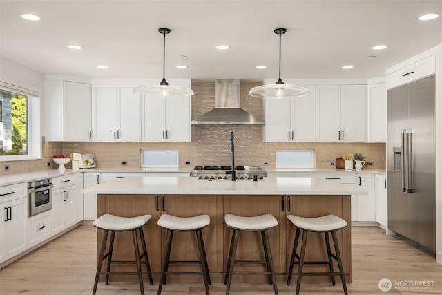 11216 NE 67th St Unit 4, Kirkland, WA 98033 - kitchen with wall chimney exhaust hood, appliances with stainless steel finishes, a center island, light wood finished floors, and tasteful backsplash