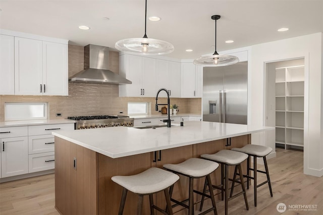 11216 NE 67th St Unit 4, Kirkland, WA 98033 - kitchen with wall chimney range hood, appliances with stainless steel finishes, light wood-style floors, decorative backsplash, and recessed lighting