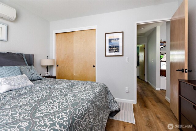 1043 NE Pennington Loop, Coupeville, WA 98239 - bedroom featuring a wall mounted AC, wood finished floors, and a closet