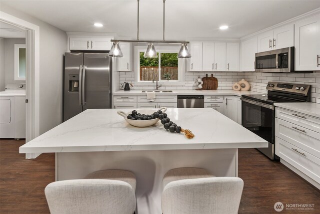 10403 Wauna St SW, Lakewood, WA 98498 - kitchen featuring appliances with stainless steel finishes, a kitchen breakfast bar, tasteful backsplash, dark wood-style floors, and white cabinets