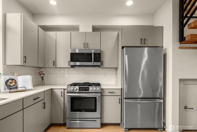 3019 62nd Ave SW Unit D, Seattle, WA 98116 - kitchen with appliances with stainless steel finishes, gray cabinetry, light countertops, decorative backsplash, and recessed lighting