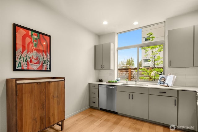 3019 62nd Ave SW Unit D, Seattle, WA 98116 - kitchen with stainless steel dishwasher, gray cabinetry, decorative backsplash, light wood-style flooring, and recessed lighting