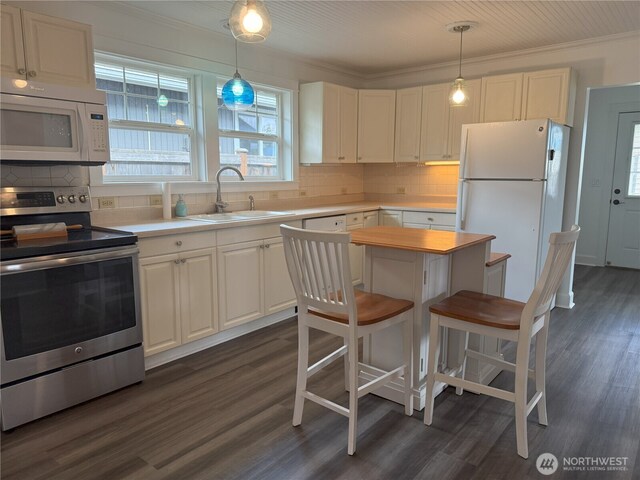 715 Ford Ave, Snohomish, WA 98290 - kitchen featuring white appliances, dark wood-type flooring, light countertops, a kitchen breakfast bar, and ornamental molding