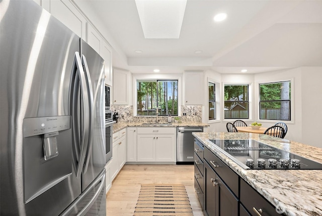 9019 166th St E, Puyallup, WA 98375 - kitchen featuring stainless steel appliances, white cabinets, light stone counters, light wood-style floors, and tasteful backsplash