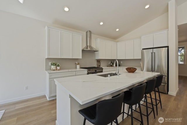 16106 Broadway Ave, Snohomish, WA 98296 - kitchen with stainless steel appliances, wall chimney exhaust hood, a kitchen bar, light wood-type flooring, and white cabinetry